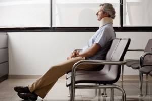 man sitting in a waiting room while wearing a neck brace