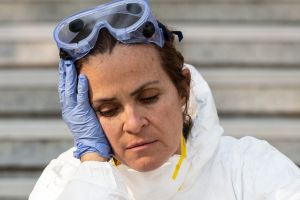 Woman holding her head being sad while wearing protecting medical equipment